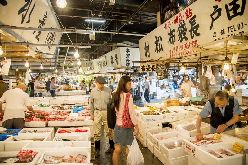 Tsukiji Outer Market in Tokyo with vendors selling fresh seafood and customers browsing